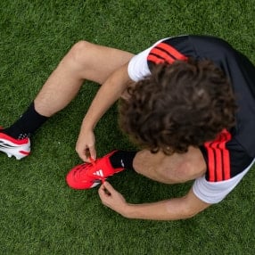 Ein Sportler bindet seine Fußballschuhe.