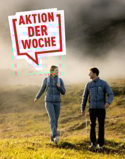 Wanderndes Paar in Funktionskleidung vor nebliger Bergkulisse mit Aktionshinweis der Woche