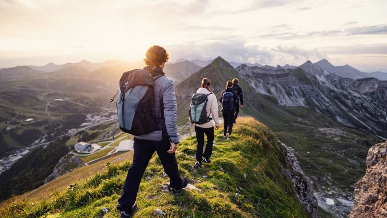 Eine Wandergruppe auf ihrem Weg zum Gipfel. Rundherum ein wunderschönes Bergpanorama bei aufgehender Sonne.