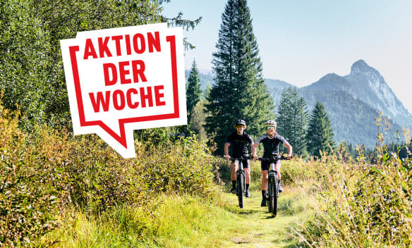 Zwei Radfahrer auf einem Weg in den Bergen bei Sonnenschein.