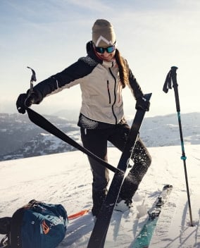 Eine Person befestigt auf einem verschneiten Berg Skifelle an ihren Skiern.