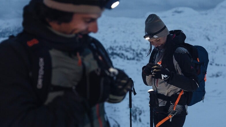 Zwei Personen mit Stirnlampen auf einer Skitour im winterlichen Gebirge.
