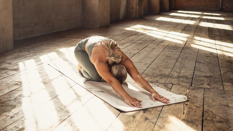 Eine ruhige Yoga Einheit kann auch bei der Regeneration unterstützen. Übungen wie hier die Haltung des Kindes entspannen Geist und Körper.