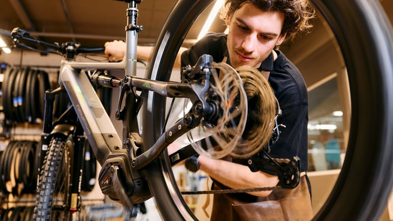 Ein INTERSPORT Mitarbeiter kontrolliert konzentriert den Zustand eines Bikes.