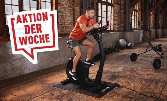 Ein Mann trainiert auf einem Fahrradergometer in einem Fitnessraum.