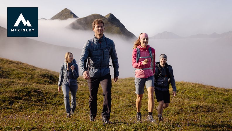 Vier junge Leute wandern in den Bergen über den Wolken.