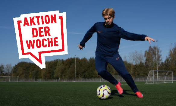 Fußballspieler in dunkelblauem Trainingsanzug mit Ball auf einem Fußballplatz, Aktion der Woche
