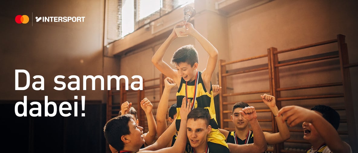 Jubelndes Basketballteam hebt jungen Sieger mit Pokal auf den Schultern in der Sporthalle hoch