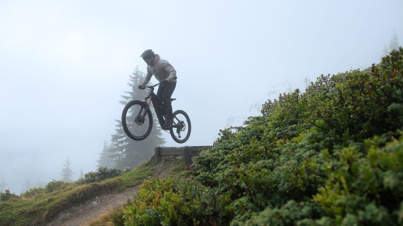 Ein Mountainbiker springt mit seinem Fahrrad durch den dichten Nebel.