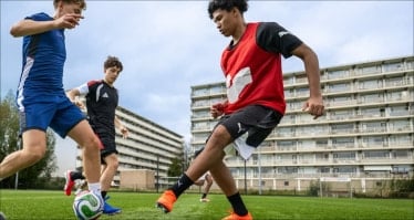 Zwei Fußballspieler kämpfen auf einem Fußballplatz in der Stadt im Zweikampf um den Ball.