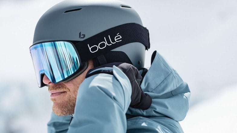 Nahaufnahme eines Mannes mit grauem Skihelm und Bollé-Skibrille.