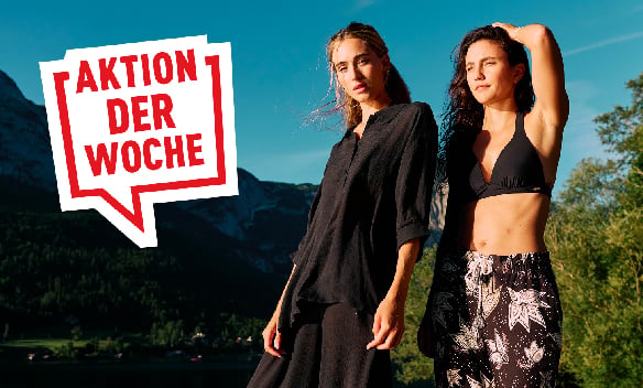 Aktion der Woche: Zwei Frauen in modischer schwarzer Sommerkleidung und Bademode vor sonniger Bergkulisse
