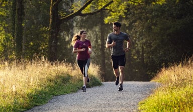 Ein Paar joggt gemeinsam auf einem Schotterweg in der Natur.