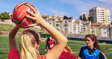Einige Frauen bei einem Fußballspiel – eine der Frauen wirft den Ball von der Seitenlinie ein.