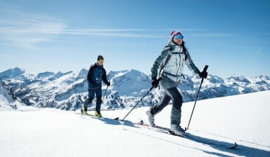 Mann und Frau auf einer sonnigen Skitour in den Bergen.