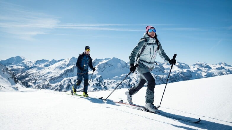 Mann und Frau auf einer sonnigen Skitour in den Bergen.