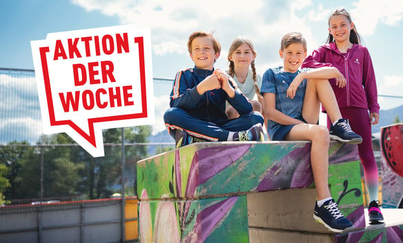 Eine Gruppe von Schülerinnen und Schülern mit Sportbekleidung auf einem Schulhof. Neben den Kindern ist eine Sprechblase mit dem Text "Aktion der Woche".