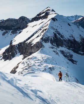 Zwei Skifahrer auf einem schneebedeckten Berg an einem sonnigen Tag.