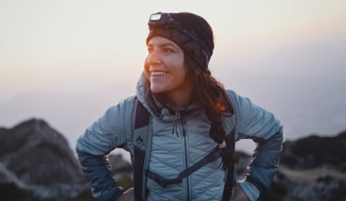Eine glückliche Frau mit Stirnlampe wandert in den Bergen.