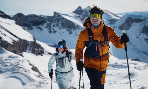 Mann und Frau bei einer Skitour in den verschneiten Bergen.