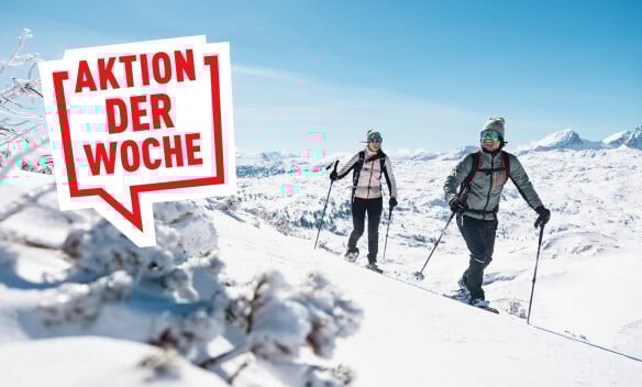 Ein Paar mit Schneeschuhen in den sonnigen, verschneiten Bergen.