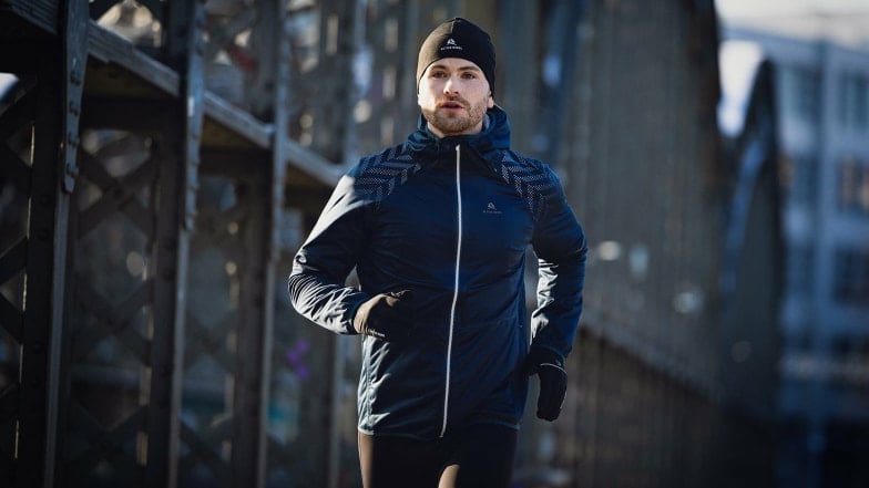 Ein Mann in Sportbekleidung läuft im Freien auf einer Brücke.
