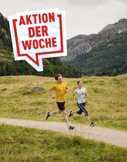 Zwei Jogger laufen durch alpine Landschaft, Sprechblase bewirbt Aktion der Woche.