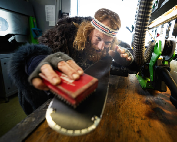 Maskot Intersportu servisuje lyže ve svém zimním kožichu v jedné ze servisních prodejen.