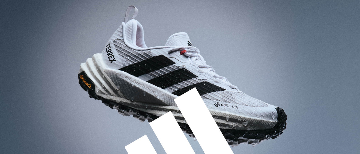 Weißer adidas TERREX-Trailrunningschuh mit schwarzen Streifen und Gore-Tex-Kennzeichnung vor grauem Hintergrund