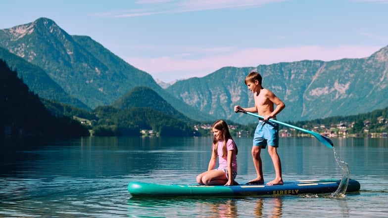 Zwei Kinder mit einem Allround-SUP von Firefly auf einem See in den Bergen.
