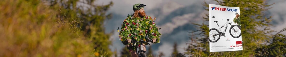 Der Frühling mit einem Fahrrad in einer Berglandschaft. Im Vordergrund die Titelseite des INTERSPORT Flugblatts.