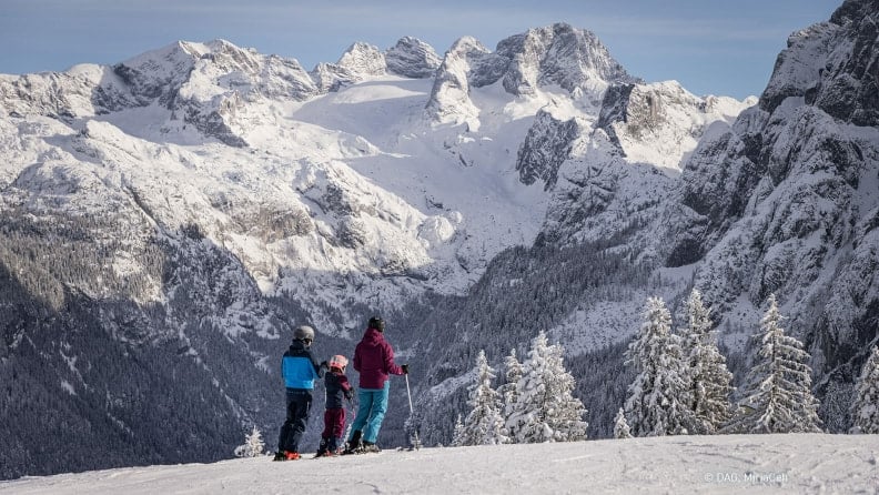 Eine Familie beim Skifahren genießt die Aussicht auf das traumhafte Dachstein Panorama. © DAG, MirjaGeh