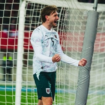 Ein Fußballspieler jubelt mit geballten Fäusten vor einem Tor. Das Tornetz ist im Hintergrund deutlich sichtbar.