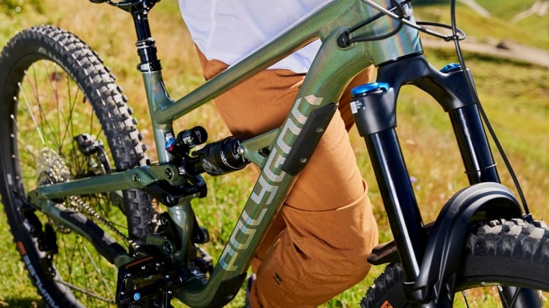 Ein modernes, grünes Mountainbike mit Vollfederung der Marke Polygon steht auf einer Wiese.
