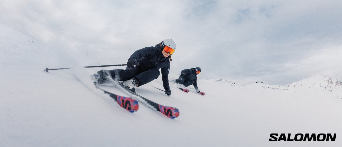Zwei Skifahrer fahren einen schneebedeckten Berg hinunter.