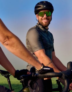 Muž na kole vyfocen od pasu nahoru s cyklistickou přilbou a brýlemi.