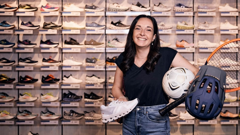 Eine INTERSPORT Mitarbeiterin mit mehreren Produkten
