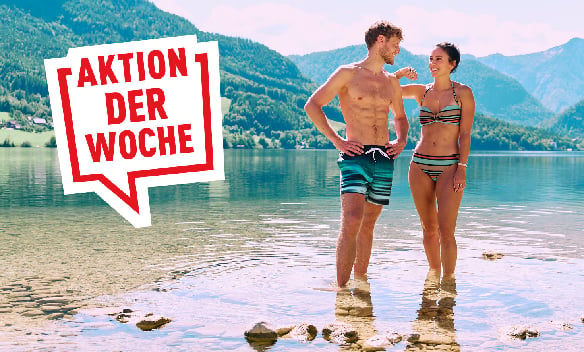 Paar in Badebekleidung steht in einem See vor Berglandschaft, daneben der Schriftzug »AKTION DER WOCHE«