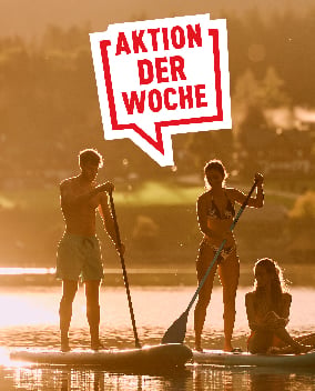 Gruppe beim Stand-up-Paddling auf einem See im goldenen Abendlicht mit Banner Aktion der Woche