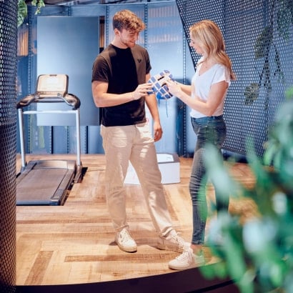 Ein Laufschuh Beratungsgespräch im INTERSPORT Shop, dahinter steht ein Energetics Laufband.
