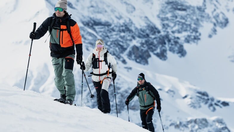 Drei Personen auf einer Skitour in den verschneiten Bergen.