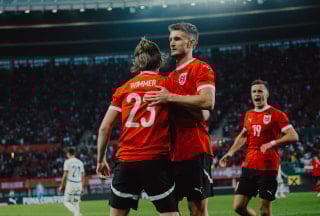 Österreichische Fußballspieler feiern nach einem Torerfolg in einem Stadion.