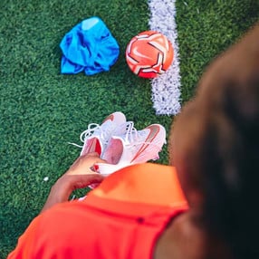 Blick von oben auf einen Ball und ein Shirt, die auf einem Fußballfeld liegen.