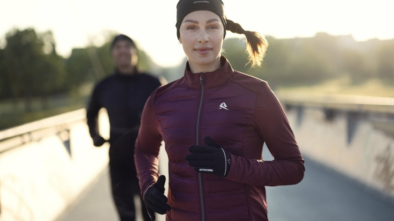 Eine Frau und ein Mann laufen draußen in Sportkleidung von INTERSPORT.