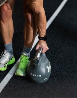 Nahaufnahme einer Hand, die eine Kettlebell vom Boden anhebt. Die Übung kräftigt Unterarme und Griffkraft.