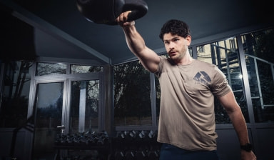 Ein Mann trainiert mit einer Kettlebell in einem  Fitnessraum.