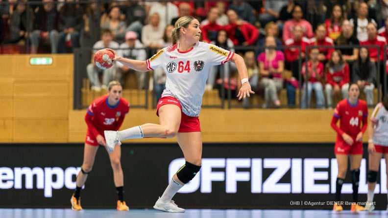 Eine österreichische Handballspielerin mit der Nummer 64 wirft den Ball.