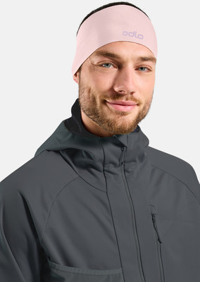 Ein Mann in einem rosafarbenen Stirnband und einer dunklen Kapuzenjacke.