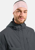 Ein Mann in einem rosafarbenen Stirnband und einer dunklen Kapuzenjacke.
