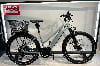 Hellgraues E-Bike mit Korb und Schutzblechen auf einem Ständer.